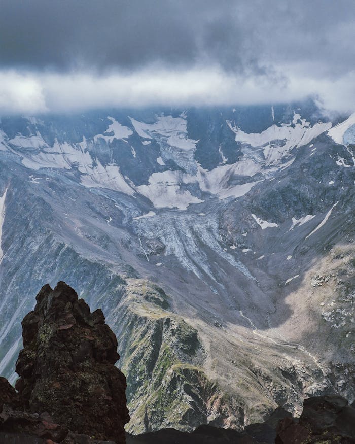 Majestic mountain vista with rugged peaks and low-hanging clouds, offering a dramatic and breathtaking view.
